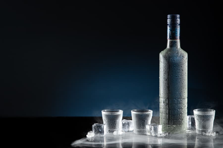 An ice-cold bottle of vodka surrounded by shot glasses